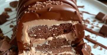 Bûche Kinder Bueno roulée au chocolat avec ganache crémeuse et décoration aux noisettes.