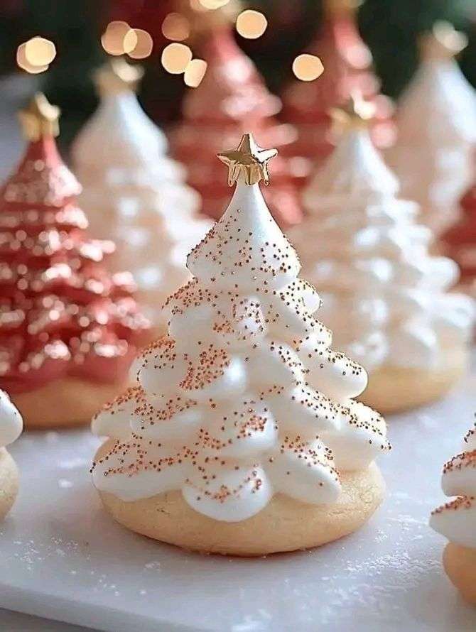 Biscuits sablés décorés de meringues en forme de petits sapins de Noël sur une plaque.