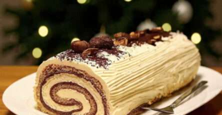 Bûche tiramisu Noël roulée, saupoudrée de cacao et décorée de grains de café