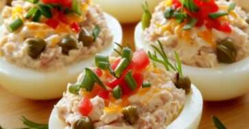 Œufs farcis thon garnis de câpres, dés de tomate, ciboulette et aneth sur un plat de service