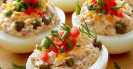 Œufs farcis thon garnis de câpres, dés de tomate, ciboulette et aneth sur un plat de service