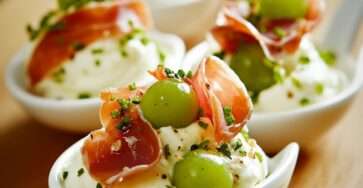 Cuillères apéritives de fromage fouetté au raisin vert et jambon cru, décorées de ciboulette