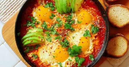 Shakshuka aux œufs et avocat avec sauce tomate, feta et herbes fraîches