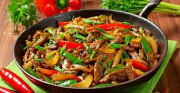 Wok de bœuf poivrons et oignons fondants sautés à feu vif dans un wok