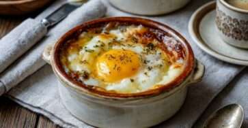 Œufs cocotte à la crème avec fromage râpé fondant et jaune coulant servis dans des ramequins