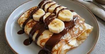 Crêpes banane chocolat pliées en triangle avec rondelles de banane, sauce chocolat fondante et sucre glace
