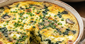 Quiche sans pâte épinards, champignons et fromage frais dorée au four dans un plat rustique avec salade verte.