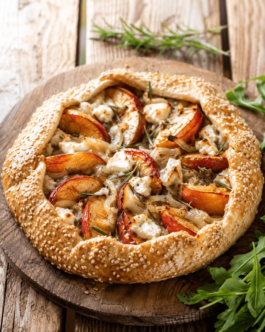 Tarte rustique nectarines salée au chèvre frais et romarin dorée au four sur une table rustique avec salade fraîche.