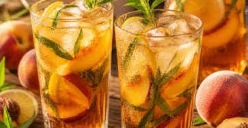 Deux verres de thé glacé maison à la pêche avec glaçons, verveine fraîche et rondelles de citron.