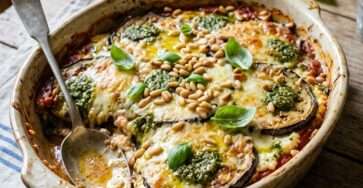 Gratin d’aubergines ricotta pesto et pignons doré au four dans un plat rustique avec basilic frais et texture fondante.