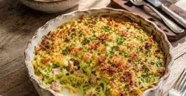 Gratin courgettes jambon et parmesan doré au four dans un plat rustique avec courgettes râpées fondantes et salade verte.